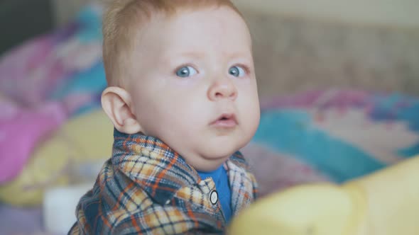 Funny Baby with Blue Eyes Plays with Wire at Playpen