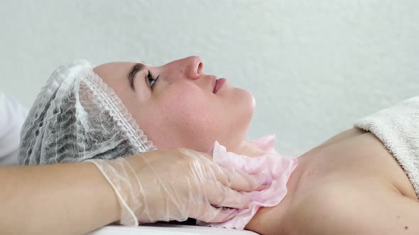 Cosmetic procedure. The face of a young woman. The hands of a female cosmetologist wipe the face