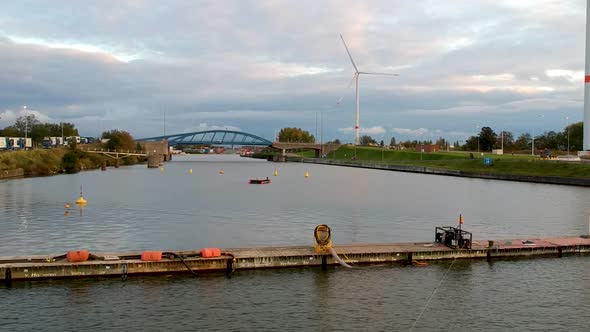 Drone flies forward towards bridge and windmills on the river Schelde.