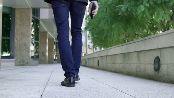 Back View of Male Legs Walking Through Passage on Pavement