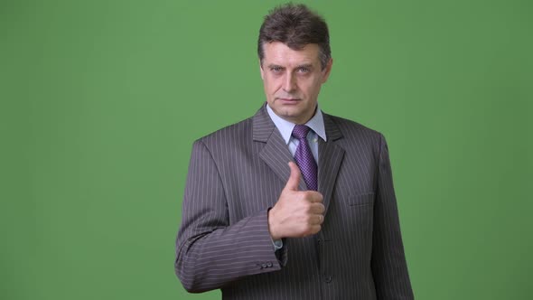 Mature Handsome Businessman Against Green Background