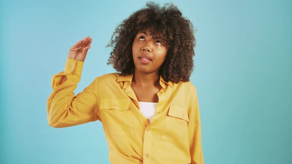 Darkskinned Lady Showing Blahblah Hand Gesture and Shrugging Her Shoulders Posing Against Blue