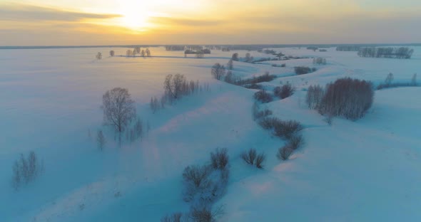 Aerial View of Cold Arctic Field Landscape Trees with Frost Snow Ice River and Sun Rays Over Horizon