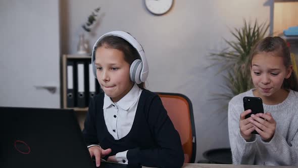 Teen Girls which Having Fun Together while Playing Video Game Using Laptop and Phone