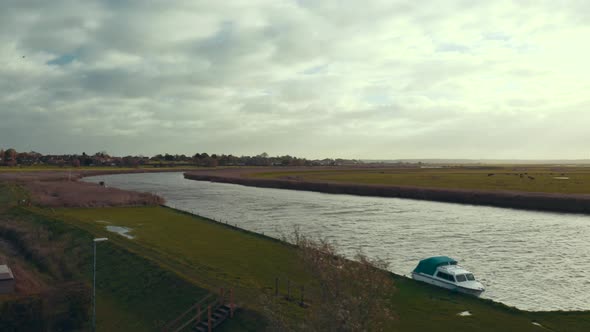 Aerial drone pan right flying over Norfolk Broads canal waterway in high wind on sunny day