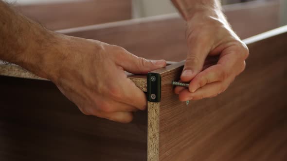 Male Hands Close-Up. Master Carpenter Collects Cabinet, Furniture, Screwing the Screw. Man's Work