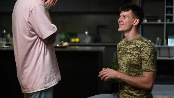 Side View Loving Gay Man Proposing to Partner Standing on One Knee at Home Indoors