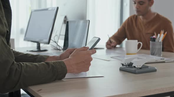 Man Scrolling on Smartphone at Workplace