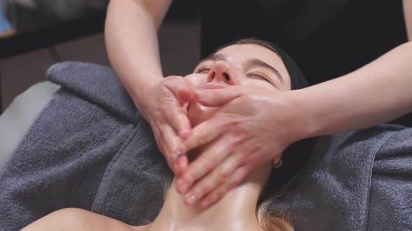 Beautiful Woman Receives a Massage of the Face and Neck Collar Area From a Professional