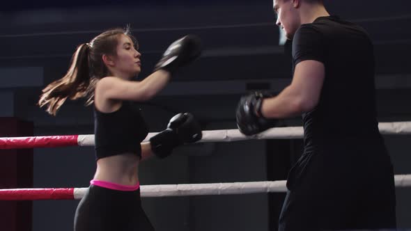 Young Woman with Long Hair Training Boxing with Her Personal Male Coach on the Ring