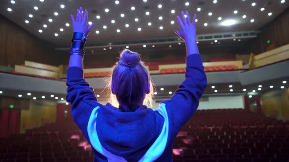 Back View of Female Singer on Big Concert Hall Stage with Empty Auditorium