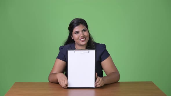 Young Overweight Beautiful Indian Businesswoman Against Green Background