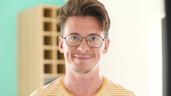 Portrait of a Smart Looking Guy with Glasses Smiling at the Camera at Home.