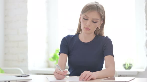 Woman Writing on Paper in Office