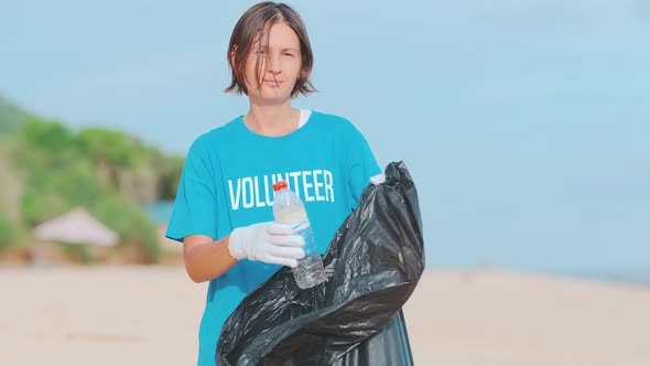 Young Pretty Caucasian Woman is Cleaning Beach From Empty Dirty Plastic Bottles