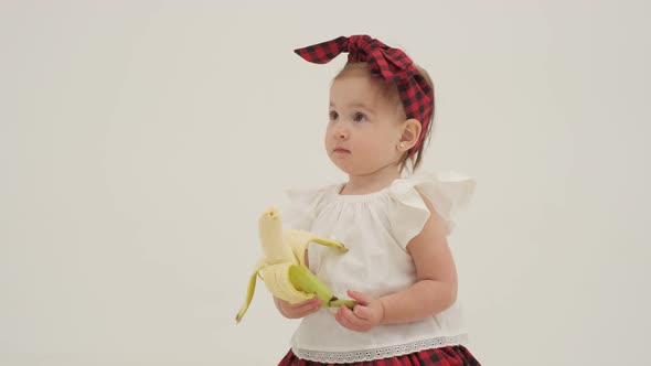 Little Girl in Plaid Headband Got a Peeled Banana