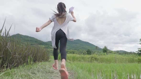 Asian Girl Running With A Paper Air Plane In Rice Field alt
