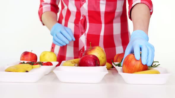 Volunteer in Protective Gloves Packs Grocery, Puts Fruits and Vegetables in Trays, Close Up