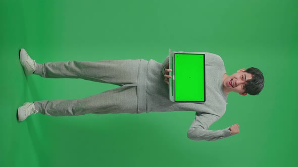 Full Body Of Happy Asian Man Celebrating While Holding Green Screen Computer In The Green Screen