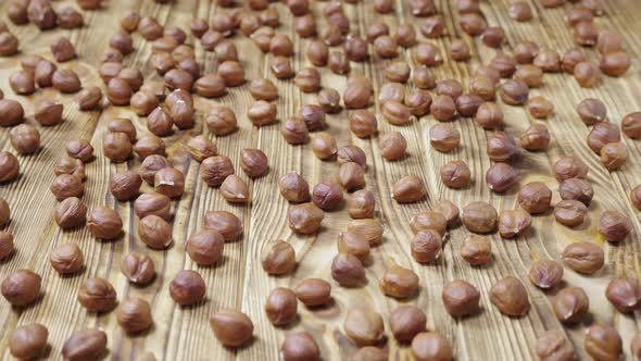 Sliding Shot of Dried Hazelnuts Lying on a Textured Wooden Table Surface