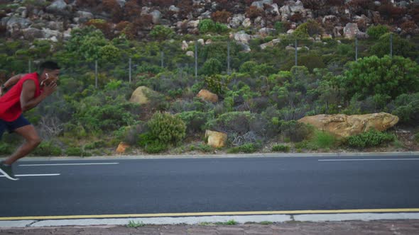 African american man wearing earphones running on the road