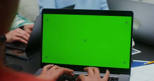 A Woman Uses a Laptop with a Green Screen While Sitting Next to Her Colleagues