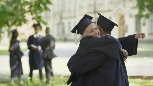 College graduates having conversation, hugging each other, university friendship