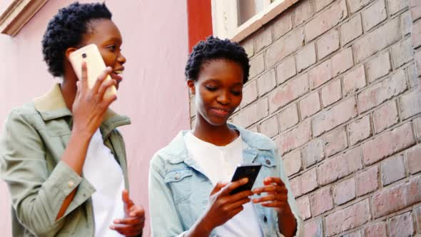 Twin sisters using mobile phone in the city 4k