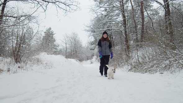 Young Beautiful Caucasian Girl And Dog Running Together In Snowy Day