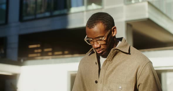 AfricanAmerican Man is Typing on a Mobile Phone While Walking in the City