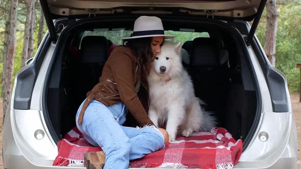 A woman is playing in nature with her four-legged friend, the dog Samoyed.