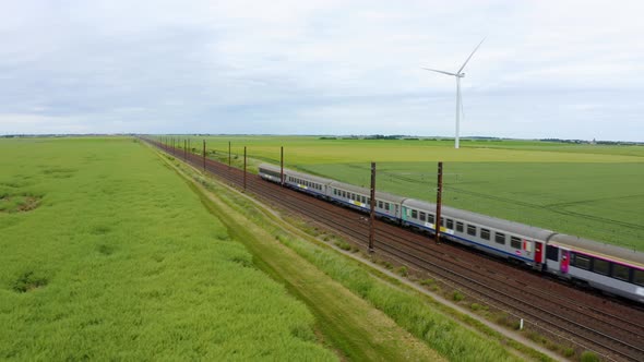 Aerial view of local train traveling through green fields 