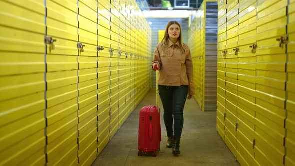 Dolly Shot of Beautiful Caucasian Woman Walking with Red Rolling Suitcase in Warehouse with Yellow