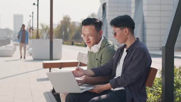 Asian Colleagues Working on Laptop Together Outdoors