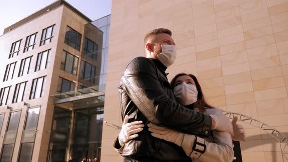 Couple in Medical Masks Standing Embracing on a Street in the City