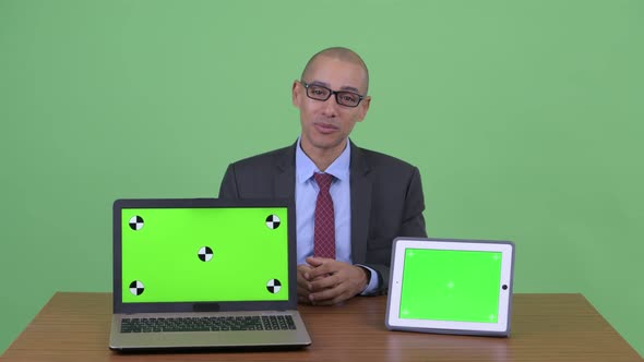 Happy Bald Multi Ethnic Businessman Presenting While Showing Laptop and Digital Tablet