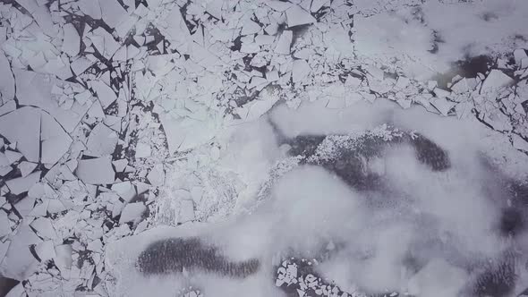 Top down drone shot flying above snowy river with big ice chunks during a winter storm in Connecticu