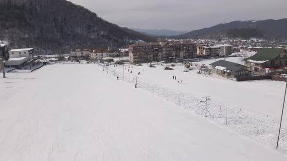 Flying over Skiers skiing climb a yoke on a mountain. people going skiing and snowboarding