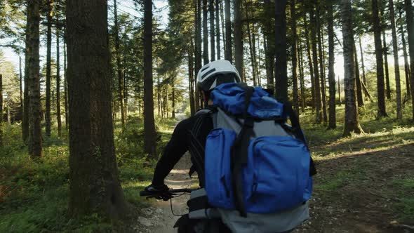 Boy Rides a Bicycle in the Mountains with Blue Backpack