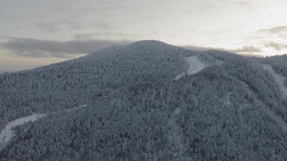 Snow dusted peak of an abandoned ski mountain at sunset AERIAL