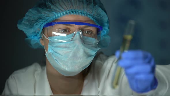 Lab Assistant Looking at Tube With Transparent Yellow Liquid, Biofuel Testing