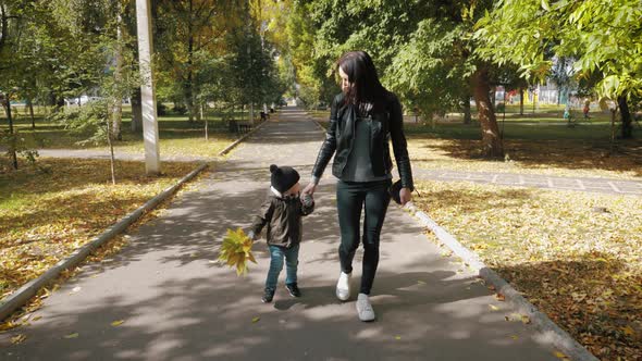 Young Mother Walking with a Little Son in Autumn Park. Happy Family in Autumn Park, Happy Family