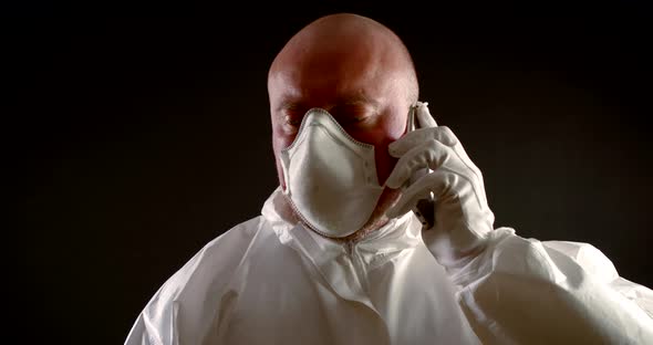 Male Health Professional with Respiratory Mask on Face Is Talking By Mobile Phone