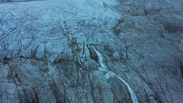 Aerial View of the Melting Glacier with Waterfall Below the Glacier