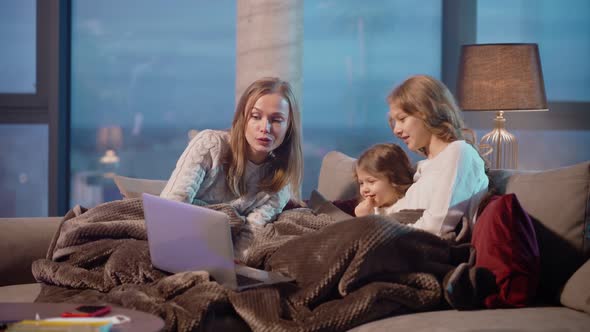 Mother with Two Daughters Having Video Call on Laptop