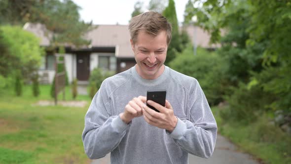 Young Happy Handsome Man Using Phone At Home Outdoors