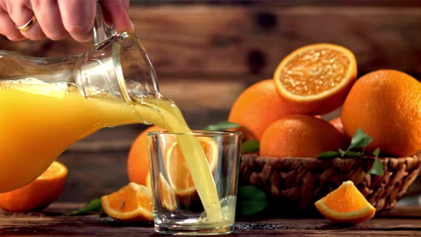 Super Slow Motion From the Jug Into the Glass Pour Orange Juice