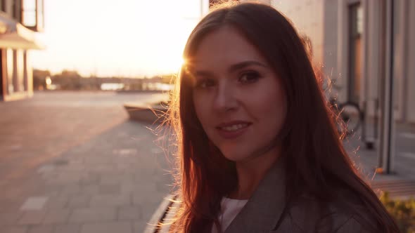 Young attractive business woman sitting outdoor on the bench. Sunset light.