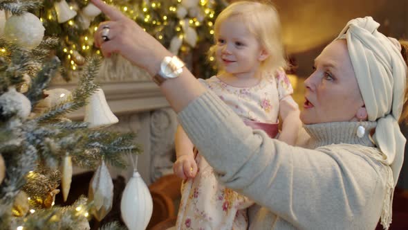 Senior Woman Showing Christmas Tree to Little Granddaughter