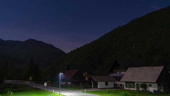 time lapse of small mountain road in Bohinj Slovenia Europe at night with cars driving by and a star